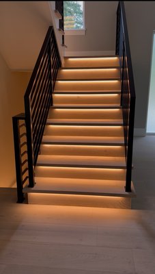 Staircase & kitchen under-cabinet LED lighting installation - Custom LED Lighting Installation
This project features a high-end, custom LED lighting installation throughout a modern home, highlighting both functionality and elegant design:
• Staircase Lighting: Installed warm white LED strip lighting beneath each stair tread, creating a soft floating effect while improving visibility and safety. Wiring was concealed for a clean, seamless look.
• Kitchen Undercabinet & Toe-Kick Lighting: Integrated dimmable LED strips under the upper cabinets and lower base cabinets to provide both ambient and task lighting. Toe-kick lighting adds depth and visual interest to the modern kitchen layout.
• Accent Cabinet Lighting: Recessed spotlights were installed above decorative display cabinets to softly illuminate upper niches, enhancing the natural wood tones and stone textures in the space.
All lighting is fully integrated into the home’s control system for dimming and smart automation, enhancing both everyday use and luxury appeal. Staircase & kitchen under-cabinet LED lighting installation - Custom LED Lighting Installation
This project features a high-end, custom LED lighting installation throughout a modern home, highlighting both functionality and elegant design:
• Staircase Lighting: Installed warm white LED strip lighting beneath each stair tread, creating a soft floating effect while improving visibility and safety. Wiring was concealed for a clean, seamless look.
• Kitchen Undercabinet & Toe-Kick Lighting: Integrated dimmable LED strips under the upper cabinets and lower base cabinets to provide both ambient and task lighting. Toe-kick lighting adds depth and visual interest to the modern kitchen layout.
• Accent Cabinet Lighting: Recessed spotlights were installed above decorative display cabinets to softly illuminate upper niches, enhancing the natural wood tones and stone textures in the space.
All lighting is fully integrated into the home’s control system for dimming and smart automation, enhancing both everyday use and luxury appeal.