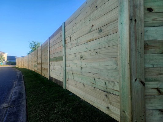 Horizontal Stockade w/1x6x8's - This custom horizontal stockade style fence was built with 9ft Aluminum Posts and Ground Contact Pressure Treated 1x6x8's. We always add a mid section support to keep all the boards level with each other. This build had 60lbs of concrete per post and 20lbs of concrete for each mid panel support rail.