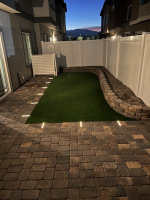 Backyard with lights installed in the floor - This was a quick installation of pavers and a planter for vegetables. Plastic was used to cover the wall and ensure it doesn’t decay over time. A new transformer and lights were installed in the walk way for a visible and beautiful view at night.