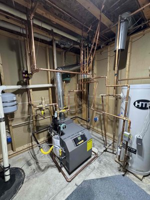 IBC Boiler Installation - Key Aspects of an IBC Boiler Installation:
Placement and Mounting: The unit is wall-mounted, often requiring a plywood backer, and should be placed where water leaks won't damage the property.
Venting and Combustion: Two holes are typically drilled through an exterior wall for direct vent (intake and exhaust). White PVC is generally used for air intake, while CPVC or special Polypropylene (PP) piping is used for the exhaust.
Piping Connections:
Heating: Copper pipes with zone pumps or zone valves are connected to distribute hot water to baseboards or radiant floor systems.
Domestic Water: Combi models (like the SL series G3) are connected to the main water supply to provide on-demand hot water.
Condensate Drain: A drain must be installed to manage the condensate produced by the high-efficiency, condensing technology.
Wiring: The unit is pre-wired, requiring 120V line voltage, along with connections for pumps and thermostat inputs.
Setup and Commissioning: The controller must be programmed during startup to configure heating loads, outdoor temperature reset, and water temperature settings. IBC Boiler Installation - Key Aspects of an IBC Boiler Installation:
Placement and Mounting: The unit is wall-mounted, often requiring a plywood backer, and should be placed where water leaks won't damage the property.
Venting and Combustion: Two holes are typically drilled through an exterior wall for direct vent (intake and exhaust). White PVC is generally used for air intake, while CPVC or special Polypropylene (PP) piping is used for the exhaust.
Piping Connections:
Heating: Copper pipes with zone pumps or zone valves are connected to distribute hot water to baseboards or radiant floor systems.
Domestic Water: Combi models (like the SL series G3) are connected to the main water supply to provide on-demand hot water.
Condensate Drain: A drain must be installed to manage the condensate produced by the high-efficiency, condensing technology.
Wiring: The unit is pre-wired, requiring 120V line voltage, along with connections for pumps and thermostat inputs.
Setup and Commissioning: The controller must be programmed during startup to configure heating loads, outdoor temperature reset, and water temperature settings.