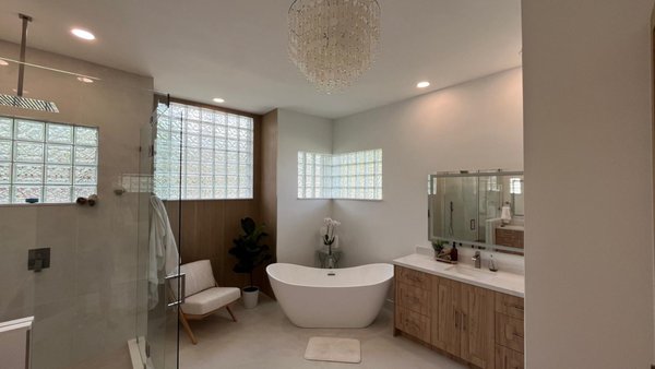 Modern Bathroom Transformation - This project transformed an outdated bathroom into a modern sanctuary of comfort and style. The new design features a freestanding soaking tub, a frameless glass shower, and custom wood cabinetry that adds warmth and sophistication. Natural light filters through glass blocks, enhancing the clean, minimalist aesthetic. Every element — from the soft lighting to the sleek fixtures — was carefully chosen to create a space that feels both luxurious and relaxing.