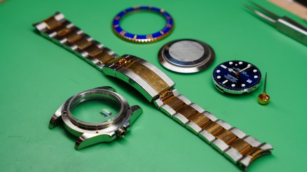 Full Overhaul on a Two-Tone Rolex Submariner: A Stunning Transformation - We recently had the pleasure of performing a full overhaul on a two-tone Rolex Submariner, and we’re thrilled to share the results! Our customer brought in this iconic timepiece, which had seen some years of wear and was due for a comprehensive service to restore its original luster and precision.

Our expert watchmakers began with a meticulous disassembly of the entire movement, cleaning each component individually to remove old oils and any accumulated debris. Once cleaned, each part was reassembled with high-grade lubricants to ensure smooth operation and long-lasting performance. We also inspected and replaced worn gaskets to ensure the Submariner met its original water-resistant standards, followed by a pressure test for ultimate reliability.

In addition to the movement servicing, we polished the two-tone case and bracelet with extreme care, restoring its original shine while preserving the watch’s contours. The end result was a beautifully restored Submariner that looked almost as good as the day it was first worn.

After a week of dedicated work, we presented the finished piece to our customer, who was thrilled with the transformation! There’s nothing more satisfying for us than seeing a happy client walk away with their watch restored to perfection, ready to make more memories.

If you’re looking to restore or service your treasured timepiece, we’re here to provide the highest level of care and expertise!
