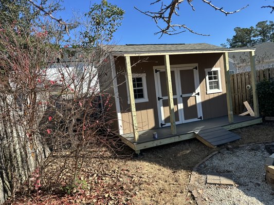 10x14 shed with front porch! - Step up your backyard game with this charming shed featuring a spacious front porch and welcoming double-door entry. The built-in ramp offers easy access for lawn equipment, bikes, or hobby gear, while the twin windows bring in natural light—perfect for a workshop, studio, or organized storage. With sturdy porch posts and a clean, modern exterior, it delivers both curb appeal and functionality. Whether you’re creating a backyard retreat or simply reclaiming space, this shed is ready to work and impress.