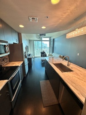 Custom Hardwood Flooring - This Nashville Condo renovation transformed an outdated space into a beautiful, modern and functional gathering space. This project includes our rich hardwood flooring that complements the home's overall design. The custom Titans logo inlay adds a unique, personalized touch, showcasing the craftsmanship and attention that Ideal Hardwood Floors is known for.