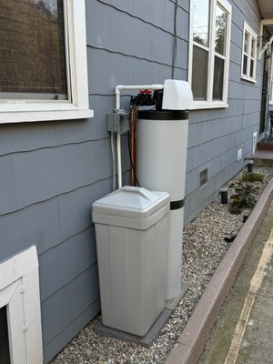 Whole-Home Water Softener & Carbon System Installation - This homeowner wanted to improve their water quality throughout the house while keeping the equipment out of sight. They didn't want the system visible from the front of the home, so we installed it on the side of the house and ran new water lines over to that location to keep everything clean and discreet.
The side yard was decorated with landscaping gravel, which doesn't provide a stable, level base for this kind of equipment. To do it right, we set concrete pavers to give the system a solid, level foundation to stand on. We then connected the unit to the nearest drain, ran a dedicated electrical outlet to power the system, and earthquake-strapped it securely to the wall — an important step here in Southern California. Finally, we filled the brine tank with salt so it was ready to go for the homeowner from day one.
The system we installed is a dual unit that combines water softening with carbon filtration. This means the hard minerals are removed to protect the home's pipes, appliances, and water heater from scale buildup, while the carbon filtration also makes the water clean and great-tasting straight from the tap. The homeowner has been enjoying soft, drinkable water throughout the entire home ever since. Whole-Home Water Softener & Carbon System Installation - This homeowner wanted to improve their water quality throughout the house while keeping the equipment out of sight. They didn't want the system visible from the front of the home, so we installed it on the side of the house and ran new water lines over to that location to keep everything clean and discreet.
The side yard was decorated with landscaping gravel, which doesn't provide a stable, level base for this kind of equipment. To do it right, we set concrete pavers to give the system a solid, level foundation to stand on. We then connected the unit to the nearest drain, ran a dedicated electrical outlet to power the system, and earthquake-strapped it securely to the wall — an important step here in Southern California. Finally, we filled the brine tank with salt so it was ready to go for the homeowner from day one.
The system we installed is a dual unit that combines water softening with carbon filtration. This means the hard minerals are removed to protect the home's pipes, appliances, and water heater from scale buildup, while the carbon filtration also makes the water clean and great-tasting straight from the tap. The homeowner has been enjoying soft, drinkable water throughout the entire home ever since.