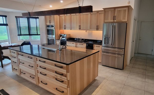 Hickory Wood Cabinet Refacing Project - This hickory wood cabinet refacing project is a stunning transformation that revitalized the look and feel of an outdated kitchen. The "before" image shows a kitchen with flat, dark wood cabinetry and a large central island that lacked the modern touch and vibrancy desired by the homeowner. The overall aesthetic appeared dated, with black countertops that contrasted with the dark cabinetry, making the space feel heavy and closed in.
The refacing project breathed new life into the kitchen by replacing the old cabinetry with beautifully crafted hickory wood. The natural light tones of the hickory wood instantly brighten the space, offering a warm and inviting atmosphere while showcasing the unique grain patterns that give the wood its distinct character. The transition from dark to light wood provides a contemporary update while maintaining the rustic charm of natural materials.
The island, once dark and plain, was transformed into a centerpiece with matching hickory panels and ample drawer storage, adding both functionality and style. The sleek black countertop was retained, providing a striking contrast against the light wood cabinetry and ensuring the kitchen remains sophisticated and modern. The new cabinet hardware, featuring modern black handles, further complements the updated look, tying the design together seamlessly.
The kitchen now boasts updated stainless steel appliances, which are perfectly integrated into the new design. These appliances add a polished, high-end feel to the room, enhancing both its functionality and aesthetic appeal. The under-cabinet lighting also highlights the beautiful wood grain and creates a warm glow that illuminates the workspace effectively.
Overall, this refacing project resulted in a total transformation, turning a once outdated kitchen into a modern, elegant, and highly functional space. The hickory wood cabinets provide a timeless appeal, while the thoughtful design updates ensure that the kitchen is not only visually stunning but also practical for everyday use. Hickory Wood Cabinet Refacing Project - This hickory wood cabinet refacing project is a stunning transformation that revitalized the look and feel of an outdated kitchen. The "before" image shows a kitchen with flat, dark wood cabinetry and a large central island that lacked the modern touch and vibrancy desired by the homeowner. The overall aesthetic appeared dated, with black countertops that contrasted with the dark cabinetry, making the space feel heavy and closed in.
The refacing project breathed new life into the kitchen by replacing the old cabinetry with beautifully crafted hickory wood. The natural light tones of the hickory wood instantly brighten the space, offering a warm and inviting atmosphere while showcasing the unique grain patterns that give the wood its distinct character. The transition from dark to light wood provides a contemporary update while maintaining the rustic charm of natural materials.
The island, once dark and plain, was transformed into a centerpiece with matching hickory panels and ample drawer storage, adding both functionality and style. The sleek black countertop was retained, providing a striking contrast against the light wood cabinetry and ensuring the kitchen remains sophisticated and modern. The new cabinet hardware, featuring modern black handles, further complements the updated look, tying the design together seamlessly.
The kitchen now boasts updated stainless steel appliances, which are perfectly integrated into the new design. These appliances add a polished, high-end feel to the room, enhancing both its functionality and aesthetic appeal. The under-cabinet lighting also highlights the beautiful wood grain and creates a warm glow that illuminates the workspace effectively.
Overall, this refacing project resulted in a total transformation, turning a once outdated kitchen into a modern, elegant, and highly functional space. The hickory wood cabinets provide a timeless appeal, while the thoughtful design updates ensure that the kitchen is not only visually stunning but also practical for everyday use.