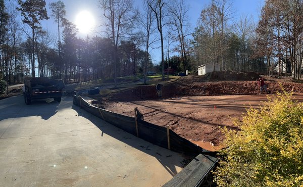 Retaining wall & patio addition 2022 - Here our customer wanted to install a Retaining Wall 70ft long along with a 30x35ft pad on the inside with a nice semi slick finish. The pad will eventually be cover and used for parking and partying. Retaining wall & patio addition 2022 - Here our customer wanted to install a Retaining Wall 70ft long along with a 30x35ft pad on the inside with a nice semi slick finish. The pad will eventually be cover and used for parking and partying.