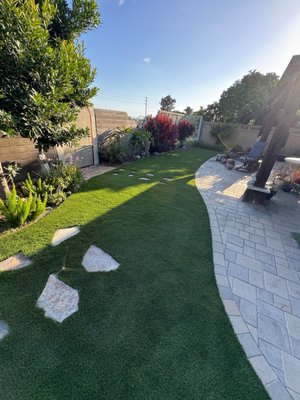 A Backyard Worth Showing Off - This backyard brings together lush artificial turf, beautifully installed pavers, and a natural flagstone pathway for a seriously stunning finish. Every texture and detail complements the next, creating a polished outdoor space that looks like it belongs in a landscape design magazine. A Backyard Worth Showing Off - This backyard brings together lush artificial turf, beautifully installed pavers, and a natural flagstone pathway for a seriously stunning finish. Every texture and detail complements the next, creating a polished outdoor space that looks like it belongs in a landscape design magazine.