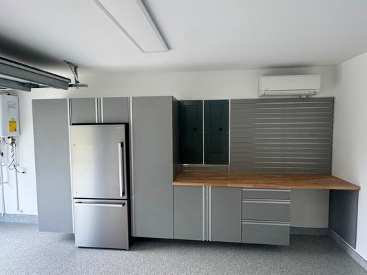 Complete Garage Makeover in Delray Beach — Custom Gray Cabinets, Butcher-Block Workbench, Slatwall Storage & Flake Epoxy Floor - This Delray Beach garage makeover took a clean, bright two-car garage and turned it into an organized, finished workspace built for the long haul. The project combined custom gray cabinetry, a solid butcher-block workbench with open shelving, a full-wall slatwall organization system, and a light-toned flake epoxy floor — a complete package that handles storage, work, and curb appeal in one pass.
The starting point was a typical builder garage: bare drywall, an exposed slab, a tankless water heater and electrical panels on one wall, and a mini-split for climate control. Good bones, but no system to it. The goal was to give the homeowner real working storage without crowding the space or fighting the existing mechanicals, and to do it in a way that still looked clean enough to leave the door open.
We began with the storage wall. A run of custom cabinets in a soft gray finish carries from floor to ceiling, with tall pantry-style cabinets flanking a center work zone. The cabinets are powder-coated and moisture-resistant — the right call for South Florida, where humidity is constant and lesser materials swell, cloud, or warp within a season or two. The doors sit flush and even, the aluminum trim detail runs straight and consistent, and the whole run reads as one continuous, intentional piece rather than a collection of boxes pushed together.
One of the smarter moves on this project was how we handled the existing electrical panels. Rather than leaving them exposed on the finished wall, we built the cabinetry around them and concealed them behind matching cabinet doors. Open the doors and the panels are fully accessible for service; close them and the wall reads clean, with no gray metal breaking up the design. That is the kind of detail that separates a thoughtful install from a quick one — keeping everything code-accessible while keeping the finished look uninterrupted.
At the center of the run sits a butcher-block workbench. The warm wood top is a deliberate contrast against the cool gray cabinets and the bright walls, giving the space a custom, almost residential feel instead of a strictly industrial one. Below the bench, base cabinets and bank drawers keep tools and hardware sorted and out of sight. Above and beside it, a section of slatwall serves as a working backsplash, ready for hooks, bins, and holders that can be repositioned as the homeowner's needs change.
On the adjacent wall, a full-width slatwall panel system extends the storage vertically across nearly the entire span. Slatwall is one of the most flexible storage solutions we install: bikes, ladders, yard tools, sporting equipment, and seasonal gear all lift off the floor and onto the wall, fully adjustable and endlessly reconfigurable. The panels were mounted dead level and run continuously wall to wall, framing the room and reinforcing the same clean horizontal lines the cabinetry establishes. A second open work surface with floating butcher-block shelving ties the two zones together.
Underfoot, the entire floor is finished in our flake epoxy coating in a light, neutral blend. Before a single coat went down, the slab was diamond-ground to open the concrete and guarantee a permanent mechanical bond — the unglamorous prep step that separates a floor that lasts a decade from one that peels in two years. The finished surface is seamless, slip-resistant, and easy to clean: it brightens the whole room, hides dust, and shrugs off hot tires, dropped tools, and chemical spills. The coating runs tight and crisp to the cabinet bases and the walls, with no overspray and no ragged edges.
What pulls it all together is consistency. The gray cabinets, the warm butcher block, the matching slatwall, and the speckled floor form a tight, deliberate palette where nothing competes. The mechanicals that the garage started with — panels, water heater, mini-split — have all been worked into the design rather than ignored or hidden poorly. The result feels calm, complete, and genuinely usable.
This is what nearly two decades of doing this work looks like: measured carefully, built to fit the actual space, and finished to a standard the homeowner will still be glad of years from now. A garage like this Delray Beach project is not just storage — it is a finished room that happens to hold cars and gear, executed with the same care a great kitchen or closet would receive. That is the standard we bring to every project across South Florida, and it is exactly what these photos show. Complete Garage Makeover in Delray Beach — Custom Gray Cabinets, Butcher-Block Workbench, Slatwall Storage & Flake Epoxy Floor - This Delray Beach garage makeover took a clean, bright two-car garage and turned it into an organized, finished workspace built for the long haul. The project combined custom gray cabinetry, a solid butcher-block workbench with open shelving, a full-wall slatwall organization system, and a light-toned flake epoxy floor — a complete package that handles storage, work, and curb appeal in one pass.
The starting point was a typical builder garage: bare drywall, an exposed slab, a tankless water heater and electrical panels on one wall, and a mini-split for climate control. Good bones, but no system to it. The goal was to give the homeowner real working storage without crowding the space or fighting the existing mechanicals, and to do it in a way that still looked clean enough to leave the door open.
We began with the storage wall. A run of custom cabinets in a soft gray finish carries from floor to ceiling, with tall pantry-style cabinets flanking a center work zone. The cabinets are powder-coated and moisture-resistant — the right call for South Florida, where humidity is constant and lesser materials swell, cloud, or warp within a season or two. The doors sit flush and even, the aluminum trim detail runs straight and consistent, and the whole run reads as one continuous, intentional piece rather than a collection of boxes pushed together.
One of the smarter moves on this project was how we handled the existing electrical panels. Rather than leaving them exposed on the finished wall, we built the cabinetry around them and concealed them behind matching cabinet doors. Open the doors and the panels are fully accessible for service; close them and the wall reads clean, with no gray metal breaking up the design. That is the kind of detail that separates a thoughtful install from a quick one — keeping everything code-accessible while keeping the finished look uninterrupted.
At the center of the run sits a butcher-block workbench. The warm wood top is a deliberate contrast against the cool gray cabinets and the bright walls, giving the space a custom, almost residential feel instead of a strictly industrial one. Below the bench, base cabinets and bank drawers keep tools and hardware sorted and out of sight. Above and beside it, a section of slatwall serves as a working backsplash, ready for hooks, bins, and holders that can be repositioned as the homeowner's needs change.
On the adjacent wall, a full-width slatwall panel system extends the storage vertically across nearly the entire span. Slatwall is one of the most flexible storage solutions we install: bikes, ladders, yard tools, sporting equipment, and seasonal gear all lift off the floor and onto the wall, fully adjustable and endlessly reconfigurable. The panels were mounted dead level and run continuously wall to wall, framing the room and reinforcing the same clean horizontal lines the cabinetry establishes. A second open work surface with floating butcher-block shelving ties the two zones together.
Underfoot, the entire floor is finished in our flake epoxy coating in a light, neutral blend. Before a single coat went down, the slab was diamond-ground to open the concrete and guarantee a permanent mechanical bond — the unglamorous prep step that separates a floor that lasts a decade from one that peels in two years. The finished surface is seamless, slip-resistant, and easy to clean: it brightens the whole room, hides dust, and shrugs off hot tires, dropped tools, and chemical spills. The coating runs tight and crisp to the cabinet bases and the walls, with no overspray and no ragged edges.
What pulls it all together is consistency. The gray cabinets, the warm butcher block, the matching slatwall, and the speckled floor form a tight, deliberate palette where nothing competes. The mechanicals that the garage started with — panels, water heater, mini-split — have all been worked into the design rather than ignored or hidden poorly. The result feels calm, complete, and genuinely usable.
This is what nearly two decades of doing this work looks like: measured carefully, built to fit the actual space, and finished to a standard the homeowner will still be glad of years from now. A garage like this Delray Beach project is not just storage — it is a finished room that happens to hold cars and gear, executed with the same care a great kitchen or closet would receive. That is the standard we bring to every project across South Florida, and it is exactly what these photos show.