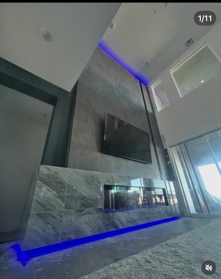 20 ft tile wall with custom fireplace - This customized 20-foot-tall fireplace mantle is a striking architectural centerpiece designed to command attention and elevate the entire space. Extending from floor to ceiling, the mantle is meticulously tiled with premium materials that add depth, texture, and visual rhythm, creating a seamless vertical statement.
Integrated LED lighting is thoughtfully embedded within the tile layout, casting a warm, ambient glow that highlights the craftsmanship and enhances the fireplace’s dramatic scale. The lighting can be customized to suit mood or occasion, adding both functionality and atmosphere.
Every detail is tailored—from the precision-cut tiles and clean lines to the custom accents that reflect the client’s unique style. The result is a bold yet refined focal point that blends modern innovation with timeless design, transforming the fireplace into a true work of art. 20 ft tile wall with custom fireplace - This customized 20-foot-tall fireplace mantle is a striking architectural centerpiece designed to command attention and elevate the entire space. Extending from floor to ceiling, the mantle is meticulously tiled with premium materials that add depth, texture, and visual rhythm, creating a seamless vertical statement.
Integrated LED lighting is thoughtfully embedded within the tile layout, casting a warm, ambient glow that highlights the craftsmanship and enhances the fireplace’s dramatic scale. The lighting can be customized to suit mood or occasion, adding both functionality and atmosphere.
Every detail is tailored—from the precision-cut tiles and clean lines to the custom accents that reflect the client’s unique style. The result is a bold yet refined focal point that blends modern innovation with timeless design, transforming the fireplace into a true work of art.