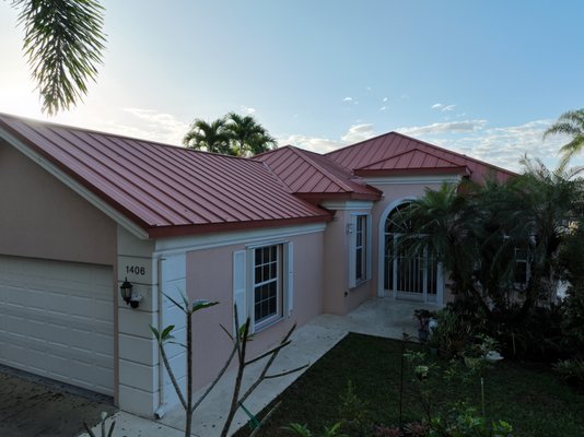 1" Standing Seam Metal Roof - Located in the heart of a premier golf community in Stuart, Florida, this residential roofing project involved a complete transformation from an aging concrete tile roof to a modern, durable standing seam metal roofing system.
We installed a USA-manufactured 1” snap lock, terra-cotta Kynar-painted steel roof—engineered for long-lasting performance and curb appeal. Custom-fabricated flashings, valleys, and drip edges were precisely fitted to ensure a watertight seal and clean lines across the entire structure.
A high-temp peel-and-stick underlayment was used for maximum heat resistance and protection beneath the panels. The homeowners now enjoy the peace of mind that comes with our 15-year workmanship warranty, tailored to withstand Florida’s climate.
Materials Used:
1” Snap Lock Standing Seam Panels
Terra-Cotta Kynar-Coated USA Steel
High Temp Peel & Stick Underlayment 1" Standing Seam Metal Roof - Located in the heart of a premier golf community in Stuart, Florida, this residential roofing project involved a complete transformation from an aging concrete tile roof to a modern, durable standing seam metal roofing system.
We installed a USA-manufactured 1” snap lock, terra-cotta Kynar-painted steel roof—engineered for long-lasting performance and curb appeal. Custom-fabricated flashings, valleys, and drip edges were precisely fitted to ensure a watertight seal and clean lines across the entire structure.
A high-temp peel-and-stick underlayment was used for maximum heat resistance and protection beneath the panels. The homeowners now enjoy the peace of mind that comes with our 15-year workmanship warranty, tailored to withstand Florida’s climate.
Materials Used:
1” Snap Lock Standing Seam Panels
Terra-Cotta Kynar-Coated USA Steel
High Temp Peel & Stick Underlayment