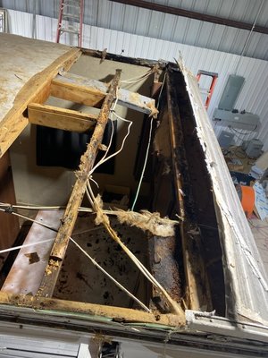RV Roof & Ceiling Repair - This is the result of water damage to the roof of an RV. The water leak started at the driver's side, front corner of the RV. It most likely started from having cracks and voids in the sealant of the front transition molding, where it was evident that the customer tried to do something after the leak was found, at some point, and probably had already done a lot of the damage at that point. With the water coming in at the corner, it ran across the whole front part of the RV, and then worked its way into the ceiling where the water presented itself at the shirt closet, wall and at the 14 x 14 vent in the bedroom area.
So, unfortunately everything needed to come out - the front 4 ft. of roof (rubber roof material and decking), the insulation and the ceiling panel. The side boards, 1 x 2, 2 x 2 and 2 x 4, as supports, all have to be rebuilt and replaced. The cabinets will not have to be removed, as the water did not damage them and they are still securely mounted/solid. All of the framing will be rebuilt around the cabinet and then the new ceiling panel can be slid in and installed/secured. Then, we will come from the top side to install the new insulation in the ceiling area, and then we can install the new roof decking. Once that has been laid and attached, then we prep the roof for the rubber (TPO) roof material to be glued and laid/secured. Then, we will reattach the side moldings, the front corner moldings and then the front transition strip. We will tape (highly recommend doing instead of using Dicor sealant) the front cap/transition strip. Reinstall the 14 x 14 vent fan and tape off around it as well, and it will ALL be "Better" than new!
And, this is why we say to please inspect your roof every 4-6 mos. so something like this does not happen. Something that could cost hundreds of dollars ($$$), turns into something a whole lot more, in the range of thousand(s)s of dollars ($$$$-$$$$$).
You can inquire about our maintenance program, or just go ahead and spend a little more and do a tape job, and then you will have some peace of mind!