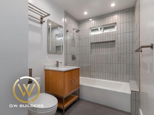Bathroom Remodel | Sausalito - This clean, minimalist bathroom features vertically stacked tile, a floating oak vanity, and brushed nickel finishes for a contemporary yet timeless feel. Every detail from the deep niche to the built-in bench was designed with simplicity, texture, and usability in mind.