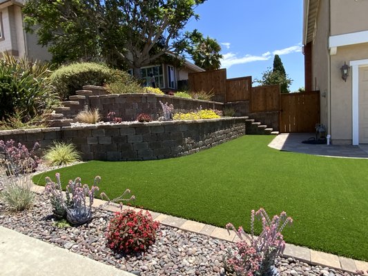 Front Yard New Landscaping & Design - This was a complete new landscape in the front yard. We demolished the existing landscape installed keysotne paver retaining walls, paver walkways, expanded the driveway, installed drain systems under the artificial turf and in the planters, installed artificial turf, installed a new drip system, installed drought tolerant plants, installed Arizona River rocks in the planters and sprayed the pavers with sealer, built custom fencing on top of the retaining walls on the slope and another section of fencing on the opposite side to match. Front Yard New Landscaping & Design - This was a complete new landscape in the front yard. We demolished the existing landscape installed keysotne paver retaining walls, paver walkways, expanded the driveway, installed drain systems under the artificial turf and in the planters, installed artificial turf, installed a new drip system, installed drought tolerant plants, installed Arizona River rocks in the planters and sprayed the pavers with sealer, built custom fencing on top of the retaining walls on the slope and another section of fencing on the opposite side to match.