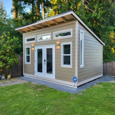 Forester Style Shed 16W X 12D - Our sheds are built for a variety of purposes. In the case of this Forester style shed, our customer in Bothell works remotely and wanted to have their own office space outside of their home.
The exterior design of this shed began with choosing a Hardie lap siding with a 7” reveal along with the painting package that we offer.
It was important for this customer to utilize as much natural light for their home office as possible. This shed was well-appointed with double full glass fiberglass doors with Weatherguard jamb, 3 Picture 4W X 1H Windows located above the doors, 2 Single-Hung 2W X 4H Windows on each side of the doors, and 2 Picture 1W X 6H Windows one on the right wall and one on the left wall. The placement and style of the doors and windows successfully achieved this customer request.
The interior of this shed was customized with white pine tongue and groove siding and snaplock flooring. For an extra fee our customers can request for us to install provided snaplock flooring.
The customer finished off the project by completing a beautiful, welcoming, cozy interior décor that puts the last touches to this stunning home office. Forester Style Shed 16W X 12D - Our sheds are built for a variety of purposes. In the case of this Forester style shed, our customer in Bothell works remotely and wanted to have their own office space outside of their home.
The exterior design of this shed began with choosing a Hardie lap siding with a 7” reveal along with the painting package that we offer.
It was important for this customer to utilize as much natural light for their home office as possible. This shed was well-appointed with double full glass fiberglass doors with Weatherguard jamb, 3 Picture 4W X 1H Windows located above the doors, 2 Single-Hung 2W X 4H Windows on each side of the doors, and 2 Picture 1W X 6H Windows one on the right wall and one on the left wall. The placement and style of the doors and windows successfully achieved this customer request.
The interior of this shed was customized with white pine tongue and groove siding and snaplock flooring. For an extra fee our customers can request for us to install provided snaplock flooring.
The customer finished off the project by completing a beautiful, welcoming, cozy interior décor that puts the last touches to this stunning home office.
