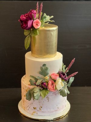 3-tiered custom wedding cake adorned with flowers and gold top tier - This lovey wedding cake is bursting with elegance! The assortment of flowers and greenery were the perfect complement to the lovely style of this modern beauty. The bride gave me free range to bring her cake vision to life and was very pleased with the result. It brought so much joy to my heart to be a part of her remarkable day and to bring happiness to such a sweet soul. 3-tiered custom wedding cake adorned with flowers and gold top tier - This lovey wedding cake is bursting with elegance! The assortment of flowers and greenery were the perfect complement to the lovely style of this modern beauty. The bride gave me free range to bring her cake vision to life and was very pleased with the result. It brought so much joy to my heart to be a part of her remarkable day and to bring happiness to such a sweet soul.