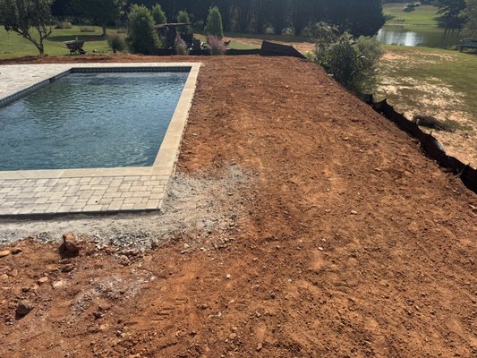 Madison Georgia Zeon Zoysia Sod installation - Before:
The pool area featured bare soil and uneven ground, leaving the backyard looking unfinished and difficult to enjoy. Mud and poor drainage made maintenance a challenge, and the space lacked the inviting, polished appearance that complements a pool setting.

After:
Premium Zeon Zoysia sod was expertly installed, creating a lush, dense, and soft lawn around the pool. The area was properly graded to ensure excellent drainage and a smooth, level surface. The vibrant green grass adds a luxurious, resort-style feel, enhancing both the beauty and usability of the backyard. Durable and heat-tolerant, Zeon Zoysia thrives in Georgia’s climate while remaining soft underfoot—perfect for relaxing, entertaining, and enjoying poolside living in Madison, GA.