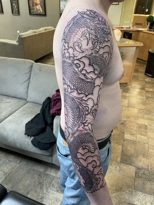 Dragon Sleeve - Title: "Ezra's Dragon Tattoo Sleeve: A Year of Artistry and Friendship"
Over the course of the past year, I had the incredible opportunity to work on one of my favorite tattoo projects ever – a dragon tattoo sleeve for my friend, Ezra. This piece holds a special place in my heart, not only because of its artistic complexity but also because Ezra showed unwavering dedication, sitting through countless hours of ink with the spirit of a true champ.
The Inspiration:
Ezra's deep affinity for dragons served as the foundation for this extraordinary project. He envisioned a magnificent dragon emerging from an enchanted mist, its scales radiating an ethereal glow. This tattoo wasn't just meant to be a piece of art; it was meant to tell a captivating story.
The Journey:
Creating a tattoo sleeve is a labor of love, a journey that requires precision and commitment. Ezra's resilience shone through as we progressed from the initial concept sketch to the meticulous shading and intricate details. Each session brought us one step closer to bringing his vision to life.
Friendship and Resilience:
This project wasn't just about ink and design; it was about the bond between an artist and a client. Ezra's dedication and trust in my vision were unwavering, resulting in an exceptional piece. Throughout the countless hours we spent working on this project, we shared stories, laughter, and celebrated life's milestones.
Ink and Memories:
Ezra's dragon tattoo sleeve stands as a testament to his passion, our enduring friendship, and the incredible journey we undertook together. It's not merely ink on skin; it's a symbol of shared experiences, friendship, and artistry.
As a tattoo artist, the true beauty lies in the stories and connections we create with our clients. Ezra's dragon tattoo sleeve embodies the profound impact of art and friendship, and it will remain a cherished part of our lives for years to come. Dragon Sleeve - Title: "Ezra's Dragon Tattoo Sleeve: A Year of Artistry and Friendship"
Over the course of the past year, I had the incredible opportunity to work on one of my favorite tattoo projects ever – a dragon tattoo sleeve for my friend, Ezra. This piece holds a special place in my heart, not only because of its artistic complexity but also because Ezra showed unwavering dedication, sitting through countless hours of ink with the spirit of a true champ.
The Inspiration:
Ezra's deep affinity for dragons served as the foundation for this extraordinary project. He envisioned a magnificent dragon emerging from an enchanted mist, its scales radiating an ethereal glow. This tattoo wasn't just meant to be a piece of art; it was meant to tell a captivating story.
The Journey:
Creating a tattoo sleeve is a labor of love, a journey that requires precision and commitment. Ezra's resilience shone through as we progressed from the initial concept sketch to the meticulous shading and intricate details. Each session brought us one step closer to bringing his vision to life.
Friendship and Resilience:
This project wasn't just about ink and design; it was about the bond between an artist and a client. Ezra's dedication and trust in my vision were unwavering, resulting in an exceptional piece. Throughout the countless hours we spent working on this project, we shared stories, laughter, and celebrated life's milestones.
Ink and Memories:
Ezra's dragon tattoo sleeve stands as a testament to his passion, our enduring friendship, and the incredible journey we undertook together. It's not merely ink on skin; it's a symbol of shared experiences, friendship, and artistry.
As a tattoo artist, the true beauty lies in the stories and connections we create with our clients. Ezra's dragon tattoo sleeve embodies the profound impact of art and friendship, and it will remain a cherished part of our lives for years to come.