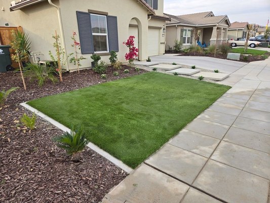 Elegant Front Yard Makeover with Modern Curb Appeal - We elevated this front yard with sleek concrete step pads, lush artificial turf, and vibrant drought-tolerant landscaping. The design features clean lines, low-maintenance elements, and a beautiful balance of greenery and stone for lasting beauty.

Services: Artificial Turf Installation, Landscaping Design