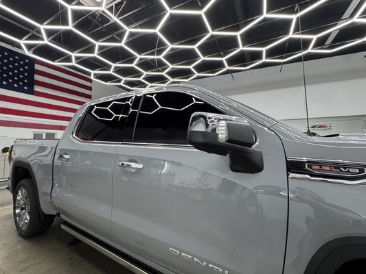 Tinting a 2025 GMC Sierra with LLumar IRX Series Ceramic Film - In this project, we transformed a brand-new 2025 GMC Sierra truck by applying LLumar IRX Series ceramic window film, a premium tinting solution designed to elevate both the aesthetics and functionality of the vehicle. The client sought a high-performance film that would enhance comfort, protect the interior, and complement the Sierra’s rugged yet refined design. After a detailed consultation, we selected the LLumar IRX Series for its advanced nano-ceramic technology and superior infrared (IR) heat-rejection capabilities, tailoring the shade to seamlessly blend with the truck’s factory-tinted rear windows.

Process:

The tinting process began with a thorough preparation of the 2025 GMC Sierra’s windows. Each glass surface was meticulously cleaned to remove any dust, debris, or oils, ensuring a flawless application. We then precision-cut the LLumar IRX ceramic film to match the exact dimensions of the Sierra’s windows, including the front and side glass. The IRX film, known for its durability and clarity, was expertly applied using professional-grade tools and techniques, resulting in a bubble-free, seamless finish. The client opted for 5% limo shade, striking a balance between style, privacy, and visibility, while enhancing the truck’s bold exterior.