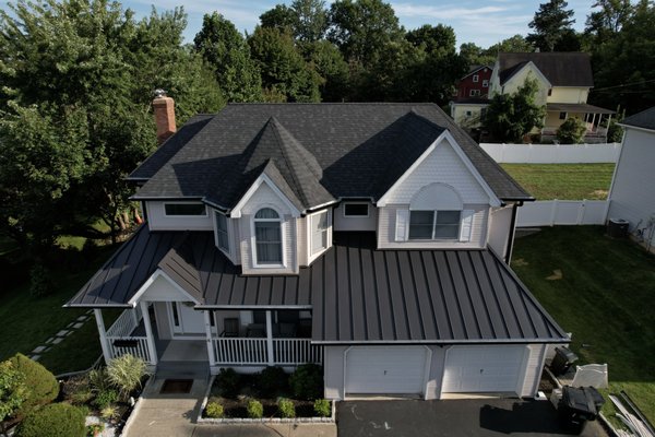 Onyx Black Shingles with Standing-Seam Metal - In 2023, we had the pleasure of transforming this home with a stunning roof upgrade. The homeowner chose Owens Corning Duration shingles in Onyx Black, bringing a bold, modern contrast to the home’s exterior. To elevate the curb appeal even further, we installed a sleek matte black standing seam metal roof over the porch and garage.
The combination of dimensional shingles and clean metal lines gave the house a dramatic, high-end look that completely changed its character. It’s a perfect example of how the right materials and expert installation can take a home to the next level. Onyx Black Shingles with Standing-Seam Metal - In 2023, we had the pleasure of transforming this home with a stunning roof upgrade. The homeowner chose Owens Corning Duration shingles in Onyx Black, bringing a bold, modern contrast to the home’s exterior. To elevate the curb appeal even further, we installed a sleek matte black standing seam metal roof over the porch and garage.
The combination of dimensional shingles and clean metal lines gave the house a dramatic, high-end look that completely changed its character. It’s a perfect example of how the right materials and expert installation can take a home to the next level.