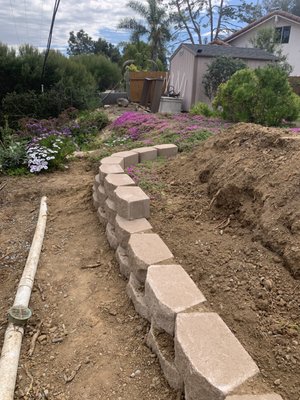 Yard leveling - Client did built 3 feet wall below but not high enough so we're adding another 3 more blocks ( keystones ) to make up the high and will level top yard out.  Client will have at least 200-300 square feet of flat back yard instead of the slope.