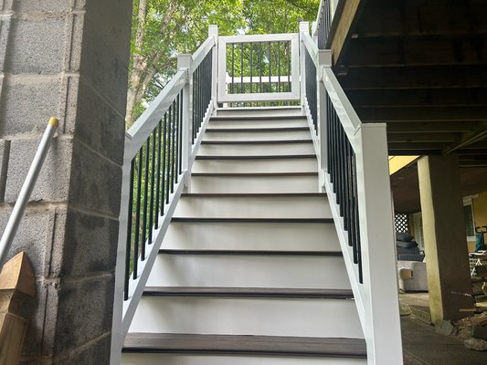 deck and railing installation with composite decking, white posts, and black balusters for a clean modern look - Exterior deck renovation with new composite decking and modern railing system installation