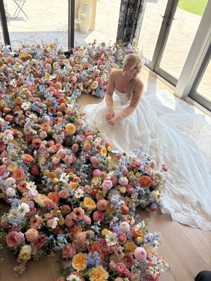 Danielle and Delan's Wedding - For Danielle and Delan's wedding, we designed a romantic, garden-inspired floral collection bursting with soft color and natural movement. The palette blended shades of blush, peach, coral, butter yellow, sky blue, lavender, and creamy ivory to create an airy, whimsical feel.
The ceremony featured a lush floral arch overflowing with premium blooms and abundant aisle meadow arrangements that framed the space with vibrant color. Reception and ceremony florals were designed with an organic, meadow-style aesthetic, creating the feeling that the flowers had naturally grown into place.
The bridal bouquet was a textured statement piece filled with garden roses, ranunculus, dahlias, delphinium, cosmos, lisianthus, hydrangeas, and seasonal specialty blooms, while each bridesmaid carried a coordinating bouquet tailored to complement the colorful mix of dresses. The result was a fresh, joyful design that felt elegant, effortless, and full of personality.
This wedding celebrated the beauty of seasonal flowers, layered textures, and playful color, creating a timeless yet modern floral experience from the ceremony through every portrait. Danielle and Delan's Wedding - For Danielle and Delan's wedding, we designed a romantic, garden-inspired floral collection bursting with soft color and natural movement. The palette blended shades of blush, peach, coral, butter yellow, sky blue, lavender, and creamy ivory to create an airy, whimsical feel.
The ceremony featured a lush floral arch overflowing with premium blooms and abundant aisle meadow arrangements that framed the space with vibrant color. Reception and ceremony florals were designed with an organic, meadow-style aesthetic, creating the feeling that the flowers had naturally grown into place.
The bridal bouquet was a textured statement piece filled with garden roses, ranunculus, dahlias, delphinium, cosmos, lisianthus, hydrangeas, and seasonal specialty blooms, while each bridesmaid carried a coordinating bouquet tailored to complement the colorful mix of dresses. The result was a fresh, joyful design that felt elegant, effortless, and full of personality.
This wedding celebrated the beauty of seasonal flowers, layered textures, and playful color, creating a timeless yet modern floral experience from the ceremony through every portrait.