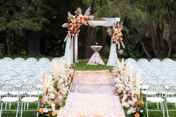 Kathrine and Mitchell Wedding - Kathrine and Michell's Wedding was a gorgeous venue with earthy tones and natural elements. We created a beautiful atmosphere with pampas grass, dried fan palms, roses, and other premium floral ingredients. Included in their wedding was aisle arrangements and a traditional wedding arch, a sweet heart table top, a welcome sign design, centerpieces, as well as personal florals for the bride and groom.
