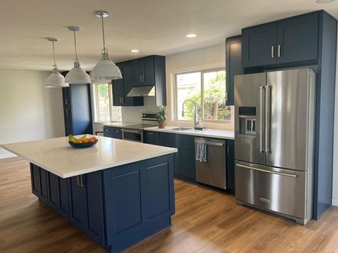 Kitchen Remodeling In Redmond, WA - This Redmond home underwent a stunning kitchen transformation, turning a dated and closed-off space into an open-concept culinary haven.
Once the structure was prepped, our team installed custom navy-blue cabinetry, adding a bold yet timeless touch. The oversized island became the heart of the kitchen, featuring a luxurious quartz countertop with ample workspace and storage. Sleek stainless-steel appliances complemented the modern aesthetic, while the new lighting arrangement, including pendant lights over the island, enhanced both functionality and style.

The flooring was replaced with warm, natural wood tones to add contrast and bring a sense of balance to the space. The backsplash, a clean and sophisticated marble-look quartz, tied the entire design together, providing both elegance and durability.

The result is a bright, contemporary kitchen that seamlessly blends practicality with high-end design. The transformation not only elevated the home’s value but also created a welcoming space for cooking, entertaining, and everyday living. This project showcases the power of expert craftsmanship, thoughtful design, and premium materials in achieving a dream kitchen remodel in Redmond.