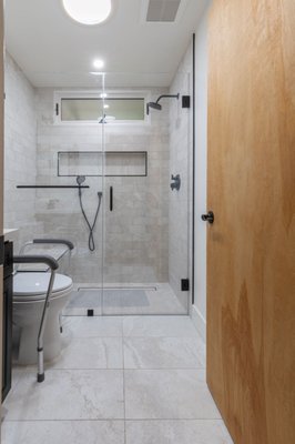 Bathroom Remodel - This elegantly remodeled bathroom blends upscale design with practical accessibility, creating a refined, spa-like retreat. Featuring a custom espresso vanity topped with polished quartz, oil-rubbed bronze fixtures, and a sleek under-mount sink, the space exudes timeless sophistication. The barrier-free, frameless glass shower showcases artisan-laid porcelain tile, a built-in bench, matte black grab bars, and dual showerheads—including a rainfall fixture—for a luxurious bathing experience. A recessed niche and linear drain add architectural interest, while the wide-format marble-look flooring and natural wood elements complete the serene, designer-inspired look. Thoughtfully crafted for both beauty and function, this bathroom remodel delivers elevated comfort with modern elegance. Bathroom Remodel - This elegantly remodeled bathroom blends upscale design with practical accessibility, creating a refined, spa-like retreat. Featuring a custom espresso vanity topped with polished quartz, oil-rubbed bronze fixtures, and a sleek under-mount sink, the space exudes timeless sophistication. The barrier-free, frameless glass shower showcases artisan-laid porcelain tile, a built-in bench, matte black grab bars, and dual showerheads—including a rainfall fixture—for a luxurious bathing experience. A recessed niche and linear drain add architectural interest, while the wide-format marble-look flooring and natural wood elements complete the serene, designer-inspired look. Thoughtfully crafted for both beauty and function, this bathroom remodel delivers elevated comfort with modern elegance.