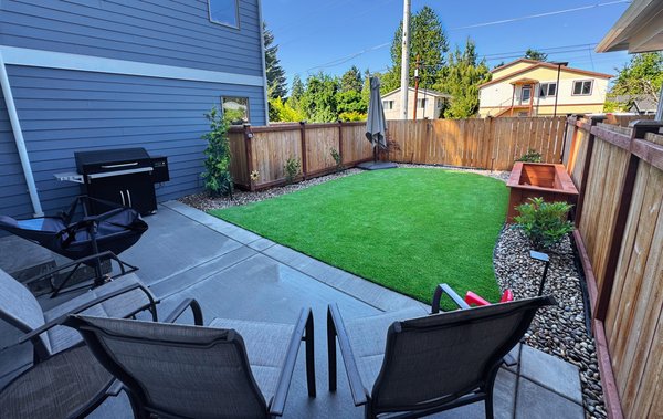 Seattle Turf Makeover - This project turned a simple yard into a serene outdoor retreat with a perfect balance of greenery and structure. The makeover includes:
• A lush turf lawn that stays vibrant year-round
• A decorative rainbow rock flower bed for added texture and contrast
• A custom cedar planter box ready for seasonal color
• Carefully selected plantings, including Camellias and Rhododendrons, chosen for year-round interest
• The main focal point: a stunning Japanese lace leaf maple, adding elegance and a touch of artistry to the design
• Subtle outdoor lighting accents to highlight the space at night
• A brand new concrete patio designed for relaxing and entertaining
The result is a backyard that blends natural beauty with low-maintenance convenience — a space designed to be enjoyed in every season. Seattle Turf Makeover - This project turned a simple yard into a serene outdoor retreat with a perfect balance of greenery and structure. The makeover includes:
• A lush turf lawn that stays vibrant year-round
• A decorative rainbow rock flower bed for added texture and contrast
• A custom cedar planter box ready for seasonal color
• Carefully selected plantings, including Camellias and Rhododendrons, chosen for year-round interest
• The main focal point: a stunning Japanese lace leaf maple, adding elegance and a touch of artistry to the design
• Subtle outdoor lighting accents to highlight the space at night
• A brand new concrete patio designed for relaxing and entertaining
The result is a backyard that blends natural beauty with low-maintenance convenience — a space designed to be enjoyed in every season.