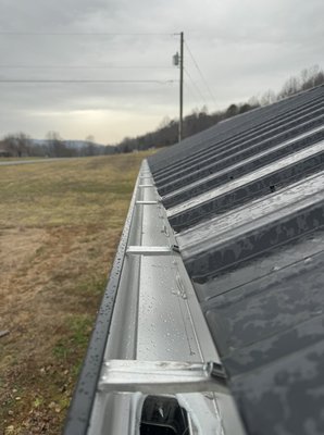 A small storage building we done last weekend - Customer had purchased a small storage building a few years ago and was having issues with water coming down from the roof causing trenches along the building.  We got the call and had this specific color in stock with the downspouts and completed the job before another downpour.  It was 28’ lengths and at 30’ you need 2 downspouts at least.  Customer told us that they wanted 2 downspouts per side.  So we set the pitch in the center of the 28’ runs and pitched both ends on both sides to the downspouts.