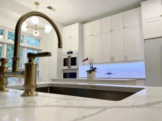 Bright kitchen remodeling! - This is a project where the softness of white Ikea kitchen cabinet doors, in combination with the height of the space, worked beautifully. The increased storage offered by two stacked rows of top cabinets created ample storage and palatial looks. Knowing the difference in shade between Grimslov and Axtad style Ikea kitchen doors, we decided the house style would blend perfectly by choosing a crisp white door like Axtad. The backsplash tile has a slight iridescent pearl hue, soaking the space in subtle iridescent light. We personalized the kitchen with brass handles. The choice of white, modern appliances with copper handles is daring, and we think it looks charming. The build-in double door oven, fridge, dishwasher, and range are GE Cafe.