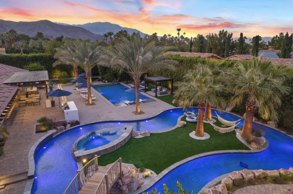 Lazy River Oasis - Lazy River Oasis is a 6300’ private, gated estate in the heart of Rancho Mirage, California. Float down the the only private lazy river in the desert, relax in the main pool, or lounge on one of the two island hammocks. The resort-like yard is walled and hedged for maximum privacy, and also includes two spas, waterslide, bocce ball, ping pong, firepit lounge, outdoor kitchen, indoor/outdoor bar, and outdoor table for 12. Interior walls of glass for Palm Springs-style indoor-outdoor living. Gourmet kitchen, living room, dining, wet bar and gym. Upstairs music and game lounge with foosball, drum set and a giant lounger for everyone to watch movies. 5 bedrooms, 5.5 bathrooms, with one being a private guest house overlooking the lazy river. Sleeps 12. Lushly landscaped, and located in an exclusive area of Clancy Lane, extremely close to golf, tennis, spas, shopping and dining.
5 Bedrooms
5.5 Bathrooms
12 Guests
6334 Sq/F Lazy River Oasis - Lazy River Oasis is a 6300’ private, gated estate in the heart of Rancho Mirage, California. Float down the the only private lazy river in the desert, relax in the main pool, or lounge on one of the two island hammocks. The resort-like yard is walled and hedged for maximum privacy, and also includes two spas, waterslide, bocce ball, ping pong, firepit lounge, outdoor kitchen, indoor/outdoor bar, and outdoor table for 12. Interior walls of glass for Palm Springs-style indoor-outdoor living. Gourmet kitchen, living room, dining, wet bar and gym. Upstairs music and game lounge with foosball, drum set and a giant lounger for everyone to watch movies. 5 bedrooms, 5.5 bathrooms, with one being a private guest house overlooking the lazy river. Sleeps 12. Lushly landscaped, and located in an exclusive area of Clancy Lane, extremely close to golf, tennis, spas, shopping and dining.
5 Bedrooms
5.5 Bathrooms
12 Guests
6334 Sq/F