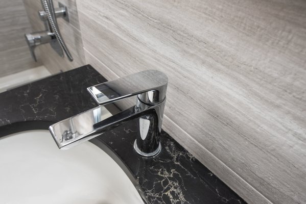 Kitchen and Bathroom Remodel in Hudson Heights - A modern bathroom featuring elegant textured wall tiles and chrome fixtures. The pedestal sink boasts a luxurious black quartz countertop, while a discreet medicine cabinet offers ample storage; completing the space is a bathtub and a convenient towel shelf for extra organization. Kitchen and Bathroom Remodel in Hudson Heights - A modern bathroom featuring elegant textured wall tiles and chrome fixtures. The pedestal sink boasts a luxurious black quartz countertop, while a discreet medicine cabinet offers ample storage; completing the space is a bathtub and a convenient towel shelf for extra organization.