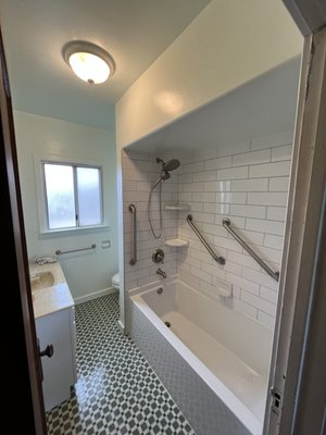 Bathroom Remodel - For this bathroom remodel the client wanted to clean up and modernize the look of the room without removing the old flooring. The result was a beautiful and bright bathroom that played nicely off the existing tile floor design. We started by demoing the bathroom walls, the tub and shower walls. We then installed new plumbing, routed new electrical for the light fixture, refinished the vanity and installed new drywall throughout. After framing out the shower niche, installing a new tub and laying new tile on the shower walls, we applied a clean coat of white paint to the walls!
