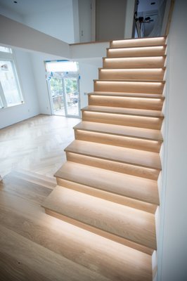 White Oak Stair Installation with LED Lighting - This project features custom white oak stair installation with integrated LED lighting under each tread. The natural white oak creates a clean, modern look, while the built-in lighting highlights each step and adds a unique architectural detail to the staircase. White Oak Stair Installation with LED Lighting - This project features custom white oak stair installation with integrated LED lighting under each tread. The natural white oak creates a clean, modern look, while the built-in lighting highlights each step and adds a unique architectural detail to the staircase.