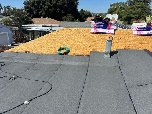 Roof Replacement Prep — Underlayment + Low-Slope Torch-Down Base - In-progress reroof. Photos show new decking installed where needed and Titanium UDL 30 underlayment being rolled out on the sloped sections. The low-slope area is being prepped with modified bitumen base sheet (ready for torch-down/cap). Owens Corning Duration Cool shingle bundles are staged on-site for the next install phase. Roof Replacement Prep — Underlayment + Low-Slope Torch-Down Base - In-progress reroof. Photos show new decking installed where needed and Titanium UDL 30 underlayment being rolled out on the sloped sections. The low-slope area is being prepped with modified bitumen base sheet (ready for torch-down/cap). Owens Corning Duration Cool shingle bundles are staged on-site for the next install phase.