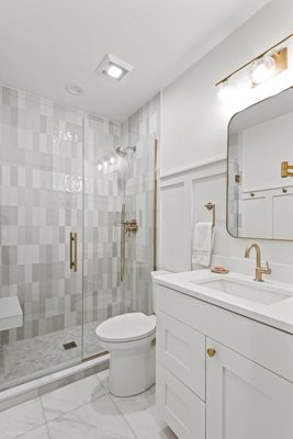 Wrigleyville- Condo Remodel - This project consisted of a complete condominium remodel including a kitchen, two bathrooms, and refreshing all rooms. 
The master bathroom is highlighted with custom board and batten wall accents and a large freestanding bathtub brightened by a chandelier. Alabaster painted double vanity is matched with a with quartz top leading to a large inviting shower. The master shower showcases a white quartz bench, handcrafted tiles, and rose gold accents throughout. 
In the guest bathroom you will find the same design flowing through highlighted by multi colored shower tiles, custom made rose gold shower door, and white marble floor tiles. 
The show-stopping kitchen features a new island adding cabinet and storage page. Alabaster white painted cabinets are complimented by the hand crafted backsplash and beautiful rose gold faucet and handles.