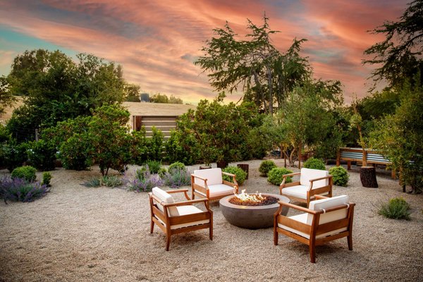 Mediterranean Sunset - This family had just finished remodeling their home and wanted a landscape that tied everything together. The property came with a steep hillside, so we carved it back and created a large, flat, functional space the kids could actually use. With a couple young ones running around, a big open lawn was a must — and we made it the centerpiece.

We poured custom concrete pathways with unique divider details and added a subtle gray tint to complement the home’s new exterior. To bring in more warmth and an organic touch, we added curated pottery groupings, gravel patios, and natural pathways.

FX Luminaire lighting was installed throughout the yard for a clean, modern nighttime look. We also installed a gas fire pit directly tied into their propane system and helped the family select the perfect fire pit setup and outdoor furniture to complete the space.