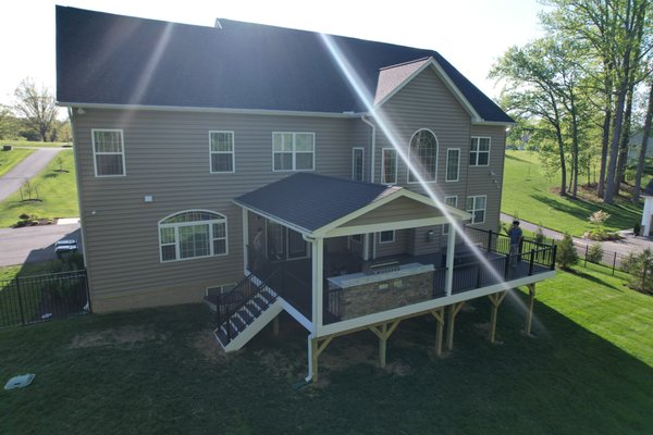 Back Deck with Roof - "Here's a stunning elevated deck featuring a built-in outdoor kitchen, perfect for entertaining. Modern railings and a stylish staircase provide convenient access. The design seamlessly integrates with the home's architecture, creating a functional and beautiful outdoor living area.