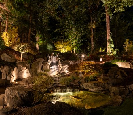 Sammamish Pine Residence - In an exclusive collaboration with Fire Sparrow Landscaping, Northwest Outdoor Lighting joined forces with the visionary Ghee for a project that redefines the essence of backyard opulence.  We designed a grandiose lighting endeavor that has successfully married functionality with sheer beauty, introducing a staggering collection of 309 meticulously placed lights that illuminate a realm of leisure and elegance.

Nestled within this illuminated paradise lies a golfer's dream—a pristine putting green, seamlessly integrated into the landscape's natural flow. But the allure doesn't stop there. Visitors are beckoned to explore the multi-tiered waterfall that cascades with a tranquil rhythm, setting the stage for an ambiance filled with serenity and charm. The firepit area emerges as a central gathering spot, where stories and warmth are shared under the starlit sky, flanked by an array of outdoor seating and dining arrangements that cater to every whim.

Not to be overlooked, the property boasts a specially designed doggie enclosed yard, ensuring that four-legged family members enjoy their own slice of the good life. Adding a touch of exclusivity and personality, Northwest Outdoor Lighting stepped in to craft custom, handmade bespoke pieces. These unique creations add layers of depth, intrigue, and substantiality, accentuating key features and transforming the property into a living piece of art.

This project is a testament to the power of collaborative creativity, skill, and vision, setting a new benchmark for luxury outdoor living spaces.

You can view more of our large portfolio on our website.