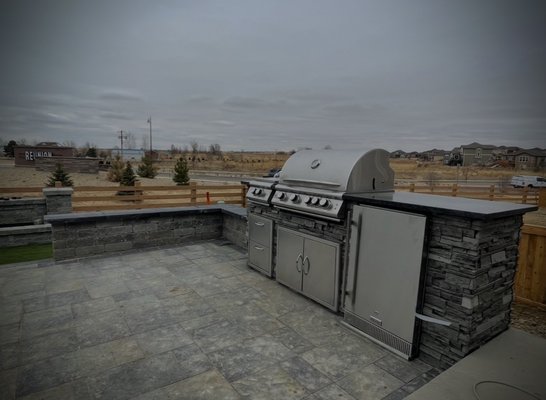 Project in Parker Co - Designed and Constructed an outdoor kitchen masterpiece: natural stone finish over cinder block, and a granite top. Complete with a grill and mini-fridge, all set on a raised paver patio. Enhanced with surrounding sitting walls for the ultimate outdoor entertaining space.