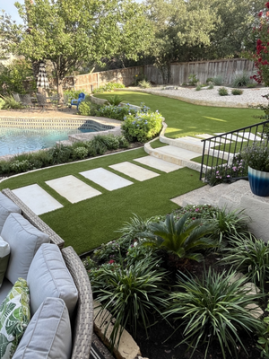 Artificial Grass Landscaping - This backyard is a perfect combination of pavers, flower beds, and artificial grass. We love every detail of this one!