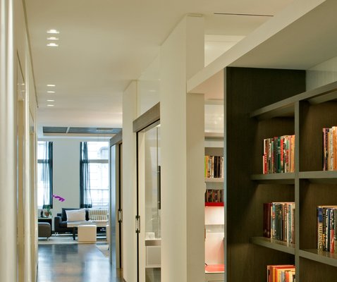 NYC Loft Renovation - Located in a historic downtown New York building, this loft has a challenging long and narrow shape, and the clients had a complex set of requirements: Both husband and wife work from home, they frequently entertain large groups, and they often have overnight guests.
In addition to the kitchen, dining room, living room and master suite, the program included his and her offices, a den, a guestroom, a sitting/TV room, a second guest space, and space for a large book collection. The challenge was to accommodate all these functions within the tight 2,200-square-foot space.

One side of the main corridor is defined by a solid wall that provides separation from the private rooms. The other side is a wood and glass system that sets off semi-private spaces. The glass, which functions as a partition between the semi-private spaces, is two-layered, encasing a semi-transparent fabric that allows natural light from large windows at the west wall to penetrate the interior space.