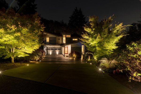 Juanita Hillside (Kirkland) - One of our most cherished contemporary projects showcases an array of sophisticated light fixture applications. The majestic trees are accentuated with strategically placed uplights at their bases, casting a dramatic glow upward. Along the stone steps and garden edges, path lights create inviting puddles of light, enhancing both safety and beauty. The waterfalls and pond are subtly illuminated using discreet, compact fixtures cleverly hidden within the rockery, ensuring the enchanting effects are only visible at night. Inspired by inlaid well lights observed in Europe during the client's holiday, we expertly replicated the look with our mini well lights. The pavers were precision-cored to accommodate the fixtures, which sit flush with the ground, perfect for highlighting the edges or uplighting the foliage along the driveway. This approach seamlessly integrates functionality with aesthetic appeal, creating an outdoor environment that is both inviting and visually stunning.

You can view more of our large portfolio on our website.