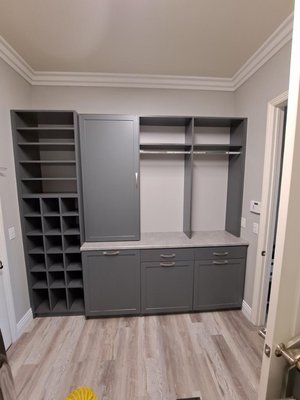 Laundry Room - This laundry room addition is built with 3/4” Storm melamine and shaker style doors. The accessories shown are: slide out ironing board, drying rack, and three tilt out hampers with removable bags Laundry Room - This laundry room addition is built with 3/4” Storm melamine and shaker style doors. The accessories shown are: slide out ironing board, drying rack, and three tilt out hampers with removable bags
