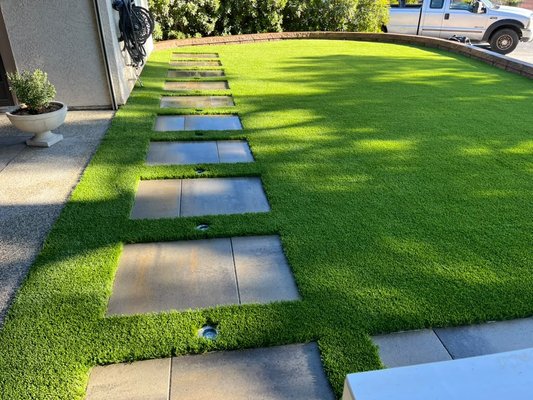 Turf with Stepping Stone Detail - This installation is all about the details. Lush artificial turf paired with perfectly placed stepping stones creates a beautifully finished backyard with crisp edges, seamless transitions, and an incredibly polished look. Sometimes a simple design executed this well is all you need. Turf with Stepping Stone Detail - This installation is all about the details. Lush artificial turf paired with perfectly placed stepping stones creates a beautifully finished backyard with crisp edges, seamless transitions, and an incredibly polished look. Sometimes a simple design executed this well is all you need.