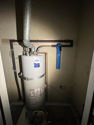 50 Gallon Water Heater Installation - This Bradford White 50-gallon gas water heater is securely installed with a galvanized flue for proper venting, seismic safety straps, and a whole-house water filtration system. The plumbing includes copper and PEX tubing, neatly secured with brackets, and a flexible yellow gas connector for the supply line. A thermal expansion tank regulates pressure, while a raised platform with a drain pan prevents water damage. The installation follows safety codes, ensuring efficient and reliable hot water delivery. 50 Gallon Water Heater Installation - This Bradford White 50-gallon gas water heater is securely installed with a galvanized flue for proper venting, seismic safety straps, and a whole-house water filtration system. The plumbing includes copper and PEX tubing, neatly secured with brackets, and a flexible yellow gas connector for the supply line. A thermal expansion tank regulates pressure, while a raised platform with a drain pan prevents water damage. The installation follows safety codes, ensuring efficient and reliable hot water delivery.